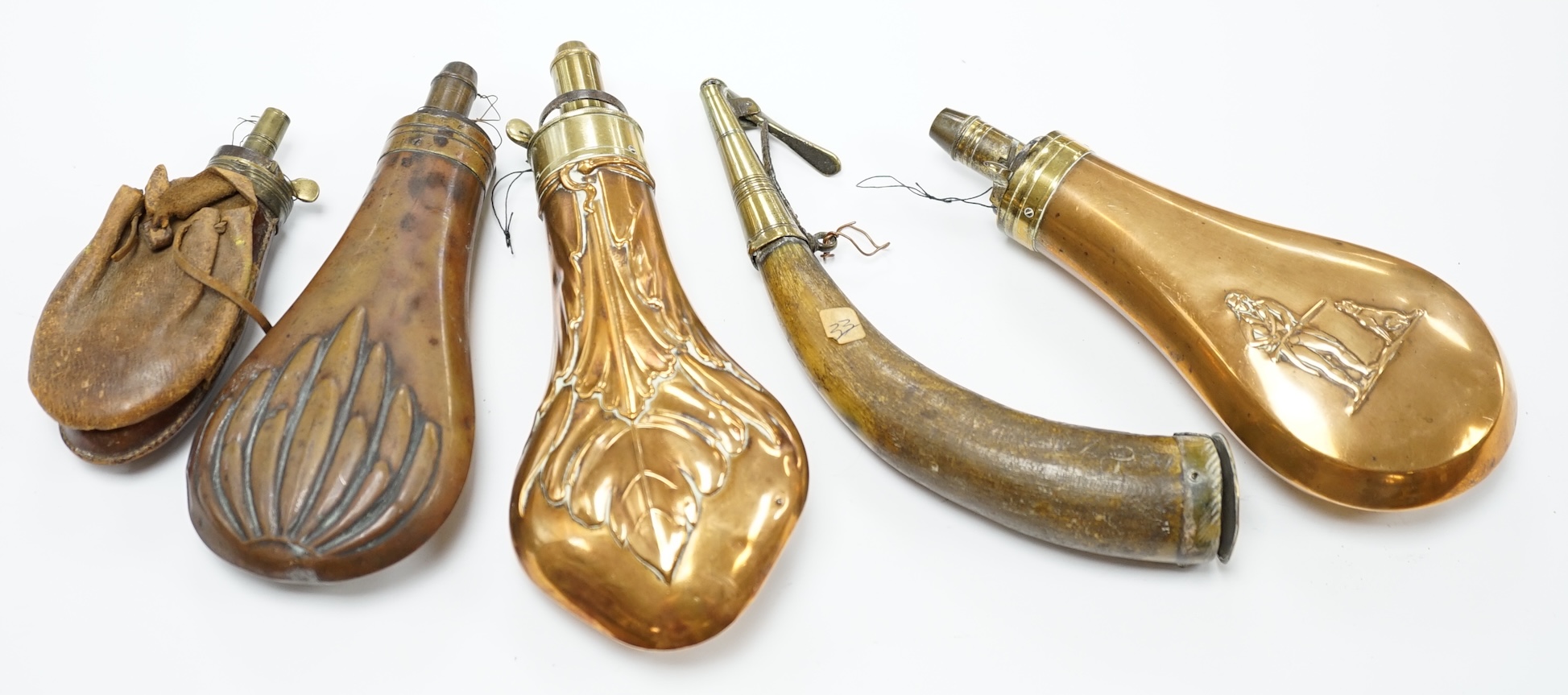 Five 19th century powder flasks; three copper and brass flasks, two with embossed decoration to the bodies, a leather covered flask and a horn Royal Artillery priming horn. Condition - poor to fair